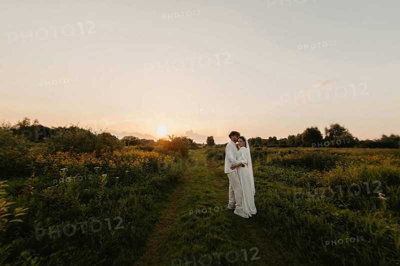 Loving couple of newlyweds at sunset in the field