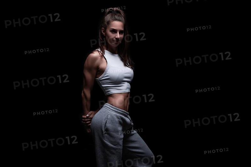 Athletic fitness woman posing in the studio on a dark background. Photo of an attractive woman in fashionable sportswear. Sports and healthy lifestyle. Mixed media