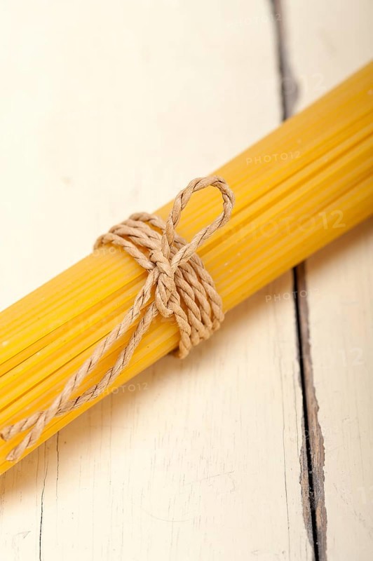 Italian pasta spaghetti tied with a rope on a rustic table