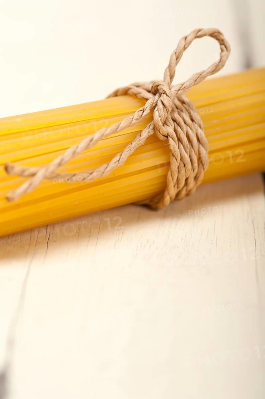 Italian pasta spaghetti tied with a rope on a rustic table