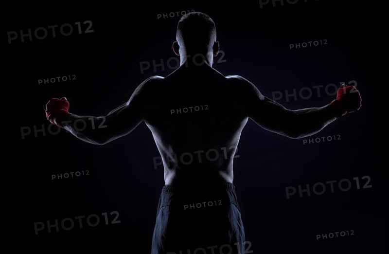 Kickboxer in red bandages raised his hands in victory. Back view. The concept of mixed martial arts. MMA