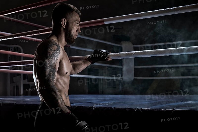 Kickboxer holding on to the ring rope. Sports competitions. Fight night. The concept of mixed martial arts. MMA