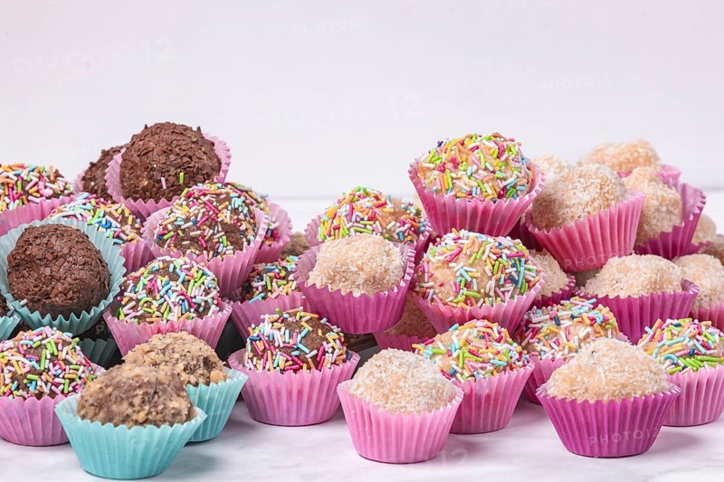 A selection of handmade light and dark rum balls on a white background