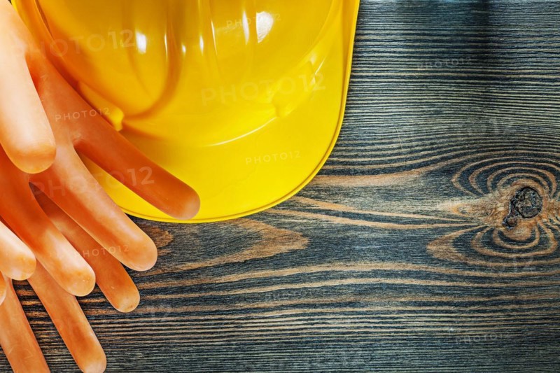 Hard hat electricians gloves on wooden board