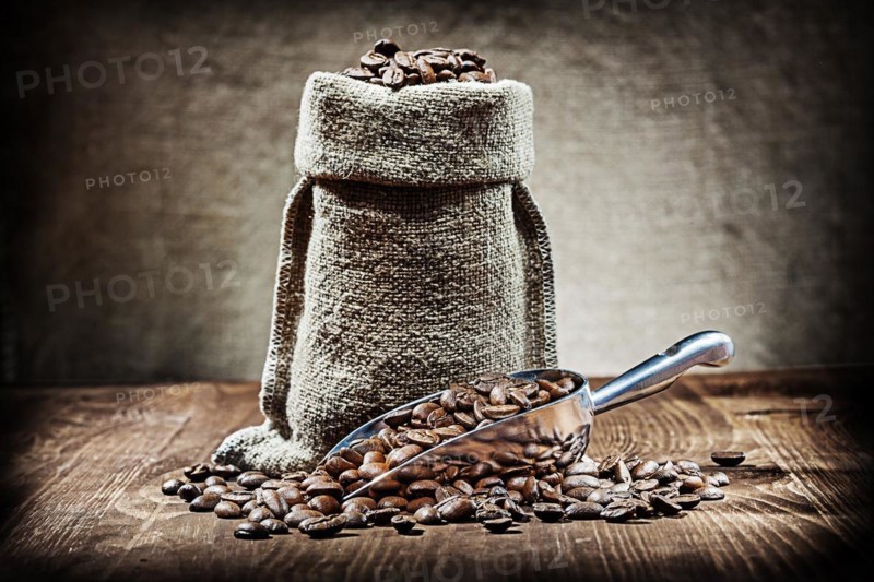 Scoop and sack with coffee beans on vintage wood table