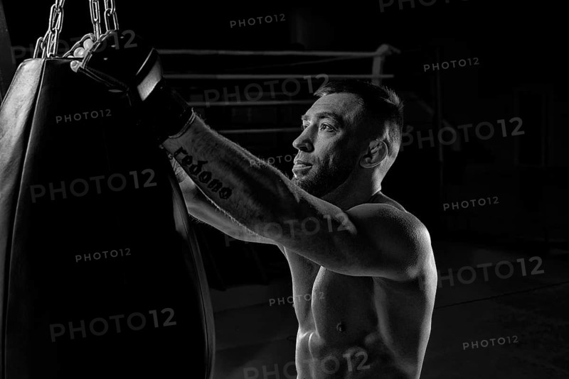 Kickboxer hooks a punching bag to a rope. Sports training. The concept of mixed martial arts. MMA