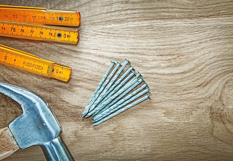 Horizontal image of claw hammer wooden meter construction nails on wood board building concept