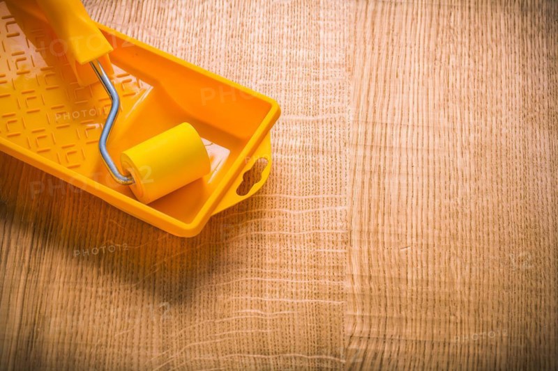 Copyspace picture yellow paint roller in tin on wooden board