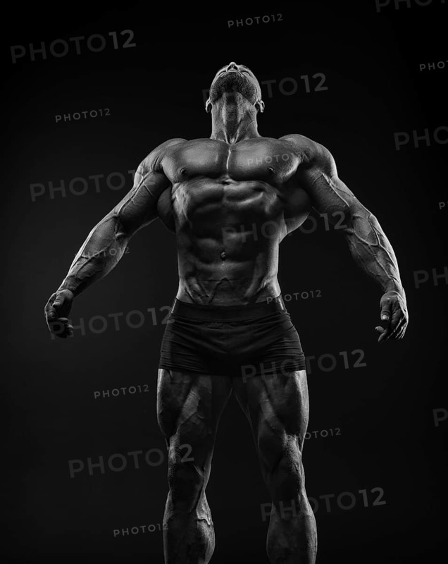 Silhouette of a strong bodybuilder. Confident young fitness athlete with a powerful body and perfect abs. Black and white photography. Dramatic light. Mixed media