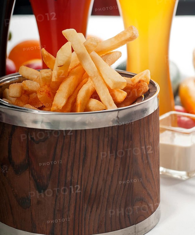 Fresh french fries on a wood bucket with selection of beers and fresh vegetables on background