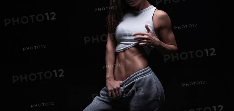 Athletic fitness woman posing in the studio on a dark background. Photo of an attractive woman in fashionable sportswear. Sports and healthy lifestyle. Mixed media