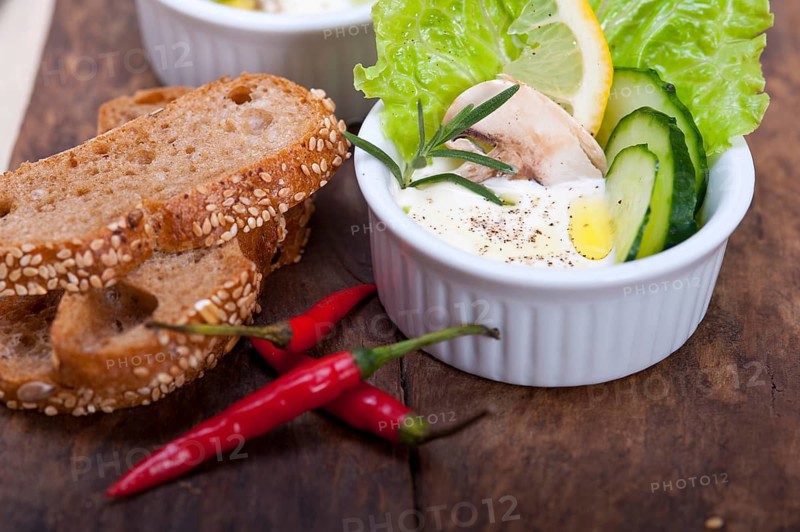 Fresh organic garlic cheese dip salad on a rustic table with bread