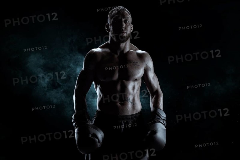 Kickboxer in black gloves posing on a background of smoke. The concept of mixed martial arts. MMA