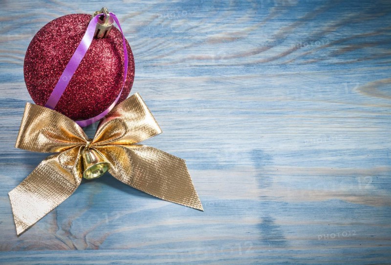 Red Christmas ball golden knot on wooden board holidays concept