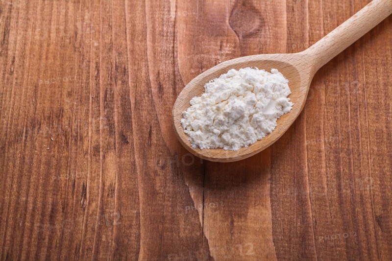 Wooden spoon with flour on old wooden board horizontal version
