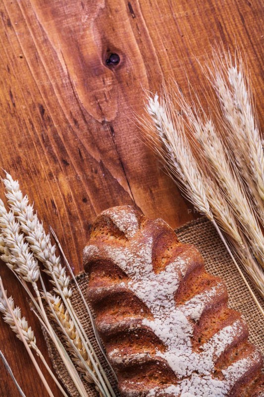 Bread and ears of wheat on a vintage wooden board Food and drink concept