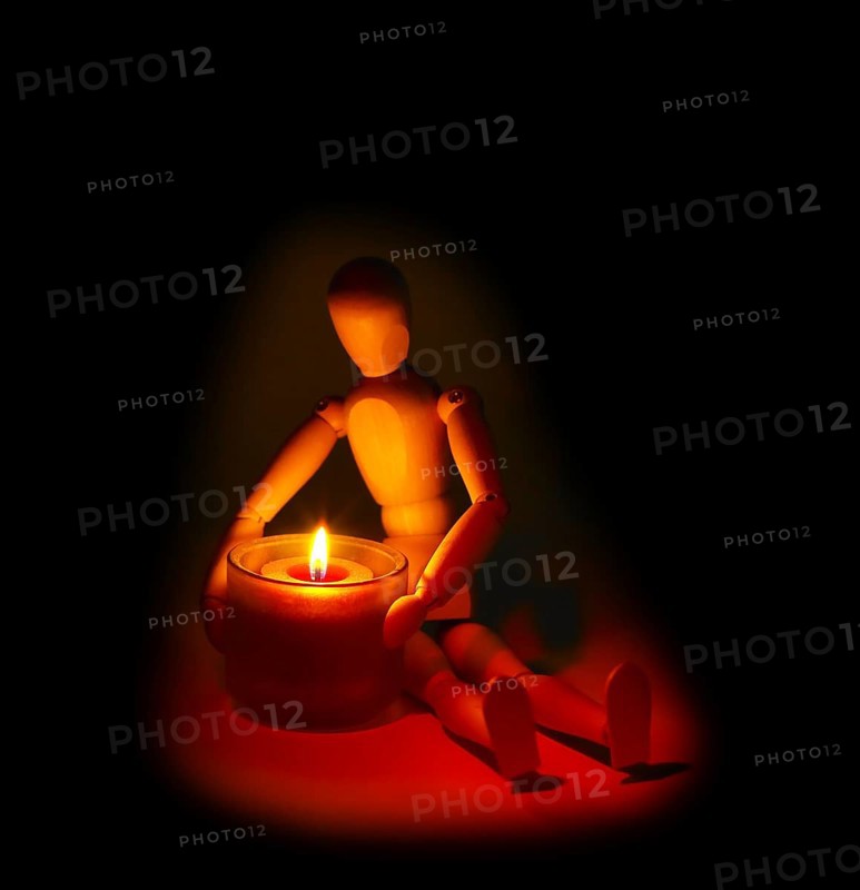 Wood mannequin and candle glowing on the dark over black background