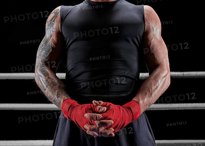 Red bandages on the hands of a kickboxer against the background of the ropes of the ring. The concept of mixed martial arts. MMA