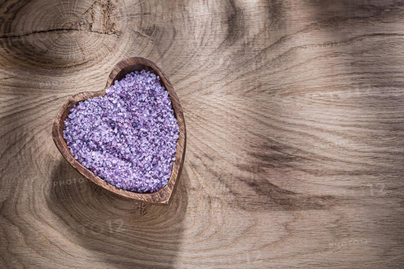 Heart-shaped bowl with lavender sea salt on wood board copy space spa treatment concept