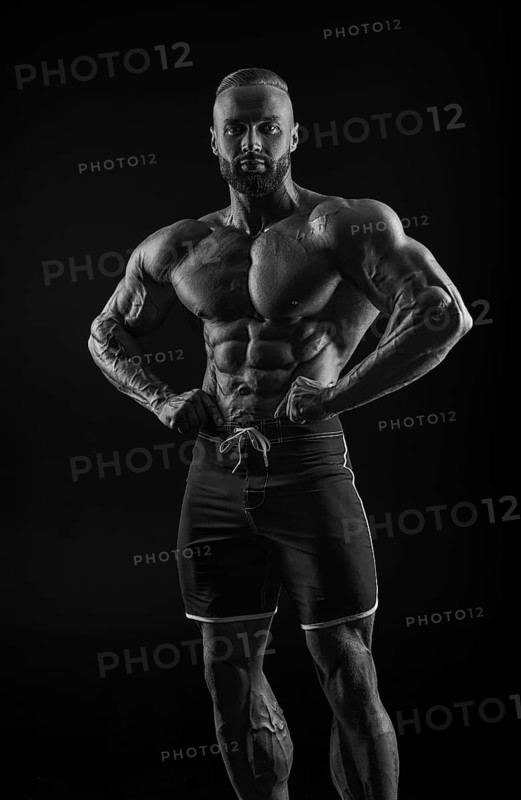 Silhouette of a strong bodybuilder. Confident young fitness athlete with a powerful body and perfect abs. Black and white photography. Dramatic light. Mixed media