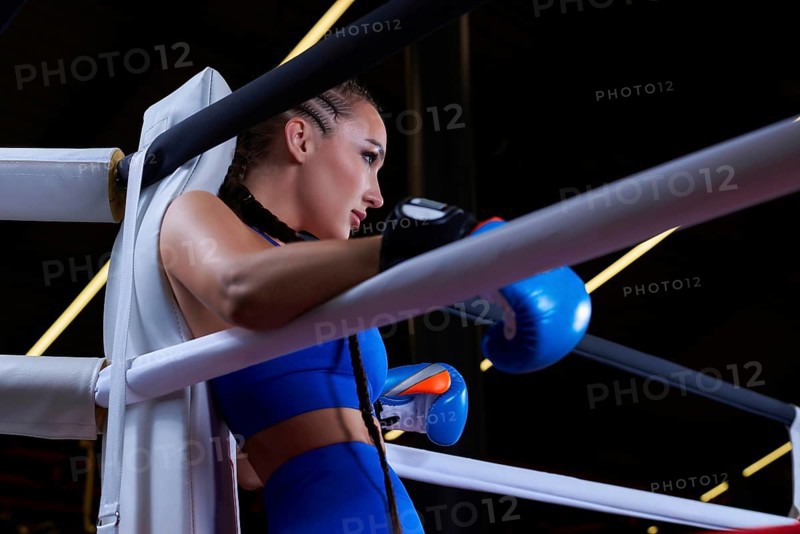 Powerful charged girl stands in the corner of the ring and is ready to explode in the next round. The concept of wrestling and boxing. Mixed media