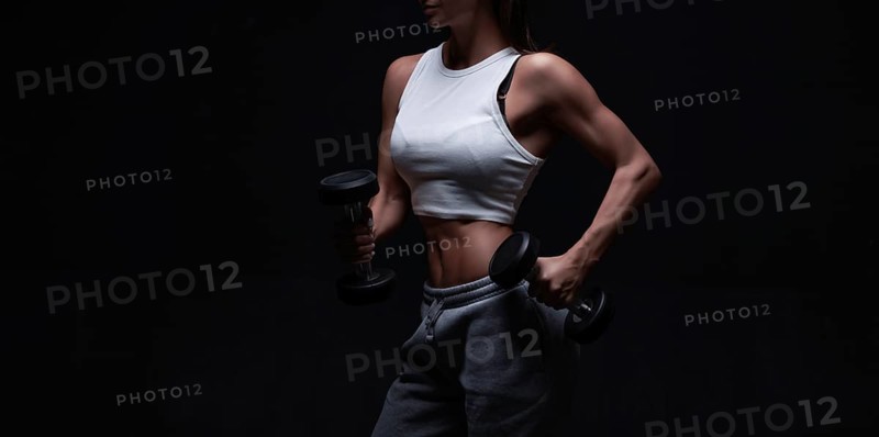 Athletic fitness woman posing in the studio on a dark background. Photo of an attractive woman in fashionable sportswear. Sports and healthy lifestyle. Mixed media