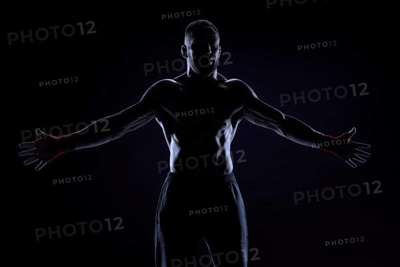 Kickboxer in red bandages poses on a blue background with his arms apart. The concept of mixed martial arts. MMA