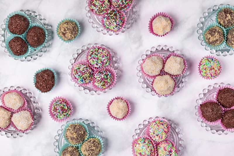 Light and dark rum balls on and next to glass plates