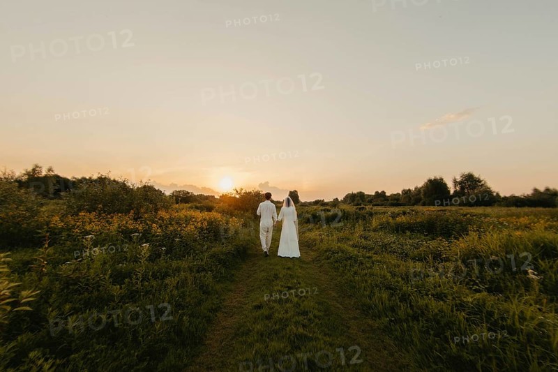 Loving couple of newlyweds at sunset in the field