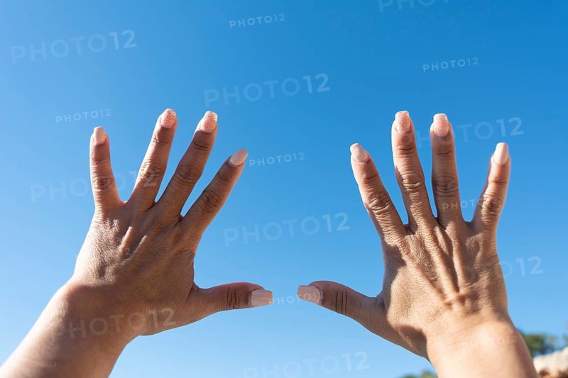 Woman's hands showing all ten fingers on a blue sky background