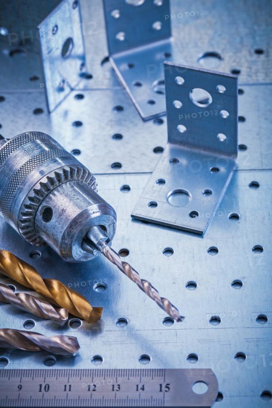 Angle fasteners bits ruler and metal drill on perforated metallic background construction concept