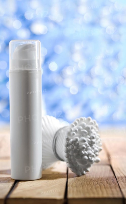 Cosmetic spray and cotton buds on a wooden table