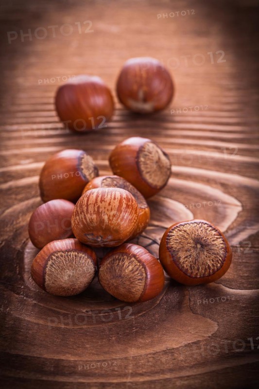 Small pile of hazelnuts on an old wooden board Food and drink Still life