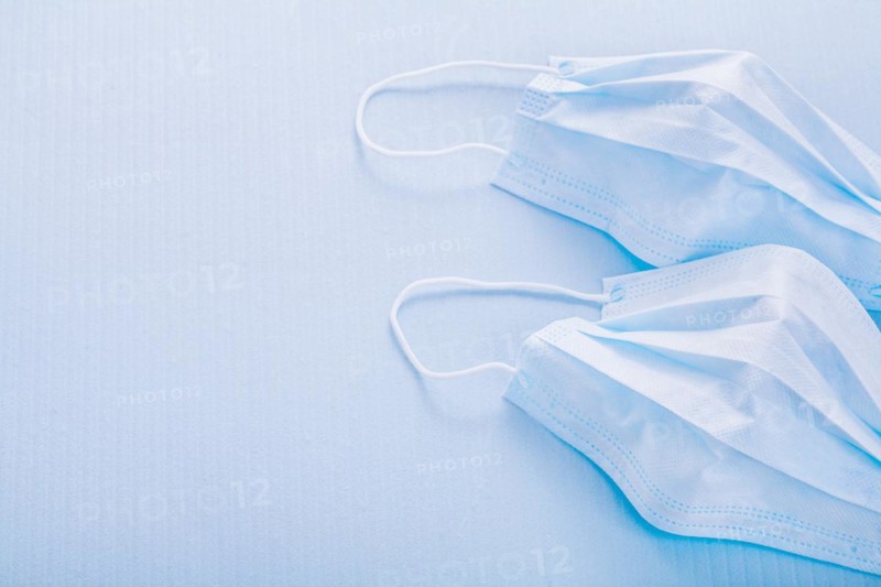 Two disposable face masks on a blue background with spaces