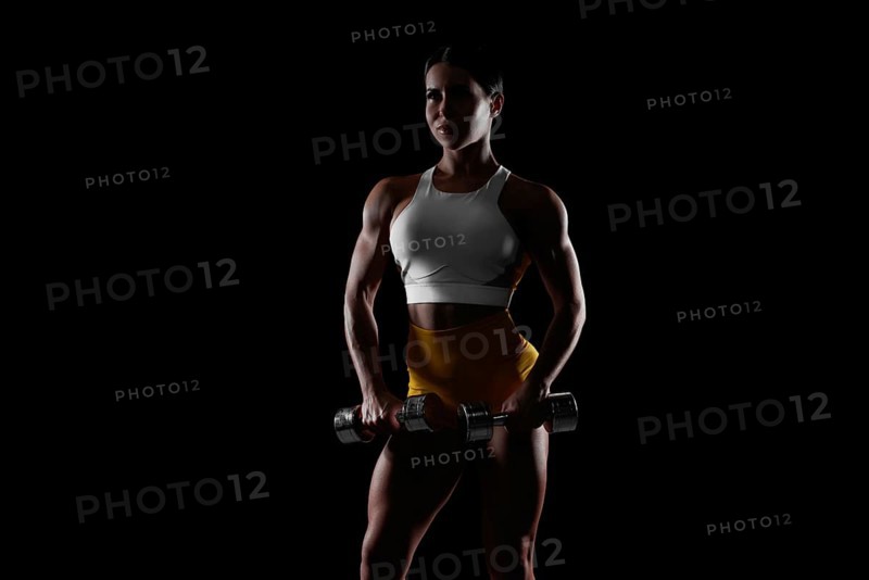 Brutal sports woman pumps up muscles with dumbbells. Fitness concept. Mixed media