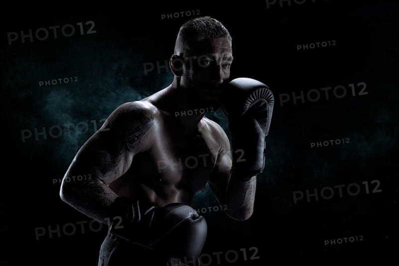 Kickboxer in black gloves posing on a background of smoke. The concept of mixed martial arts. MMA