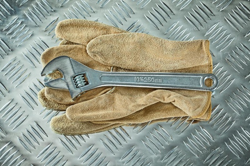 Adjustable spanner protective gloves on corrugated metal background