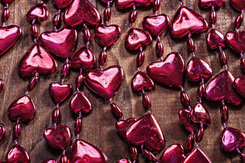 Background red valentines beads garland on old wooden board horizontal version