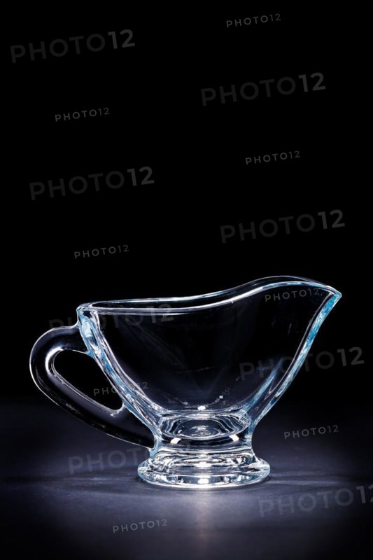 Transparent glass sauce boat on a black background