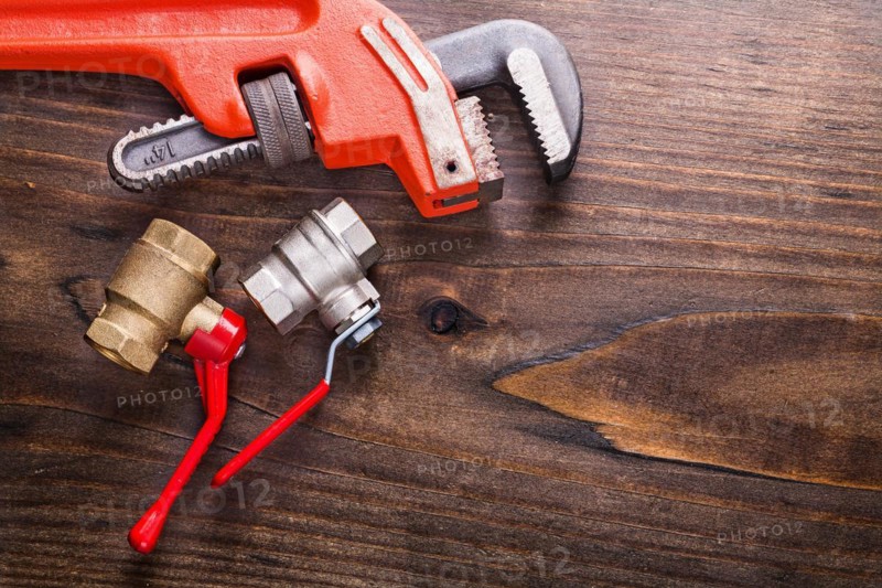 Monkey spanner and plumbing accessories on an old wooden board