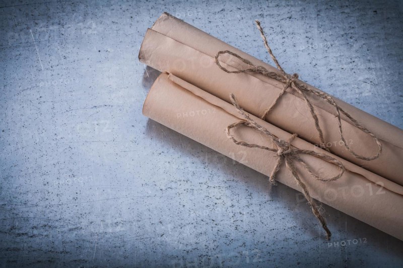 Age-old corded paper rolls on scratched metallic surface