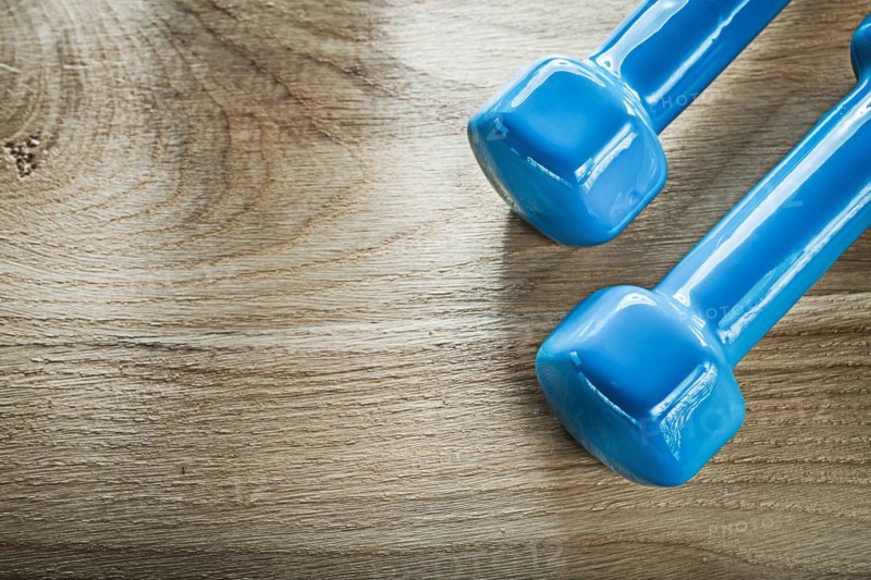 Blue dumbbell weights on wooden board fitness concept
