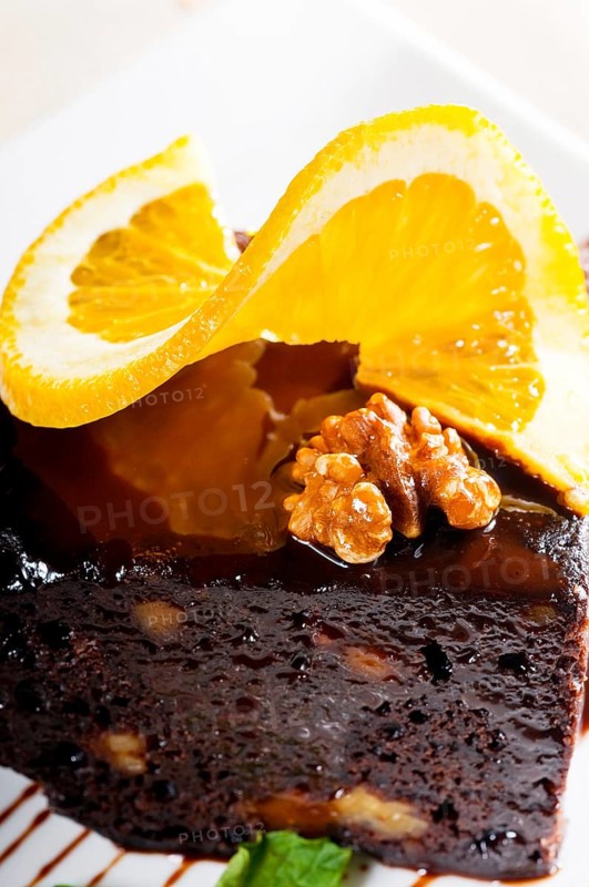 Fresh baked delicious chocolate and walnuts cake with slice of orance on top