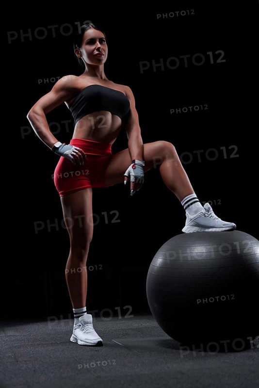 Athletic girl working out in gym. Fitness woman training with pilates ball. Mixed media