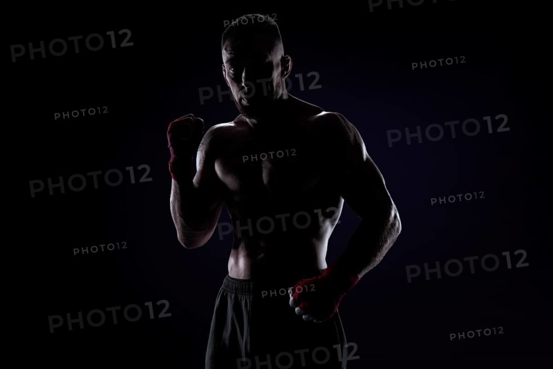 Kickboxer in red bandages posing on a blue background. The concept of mixed martial arts. MMA