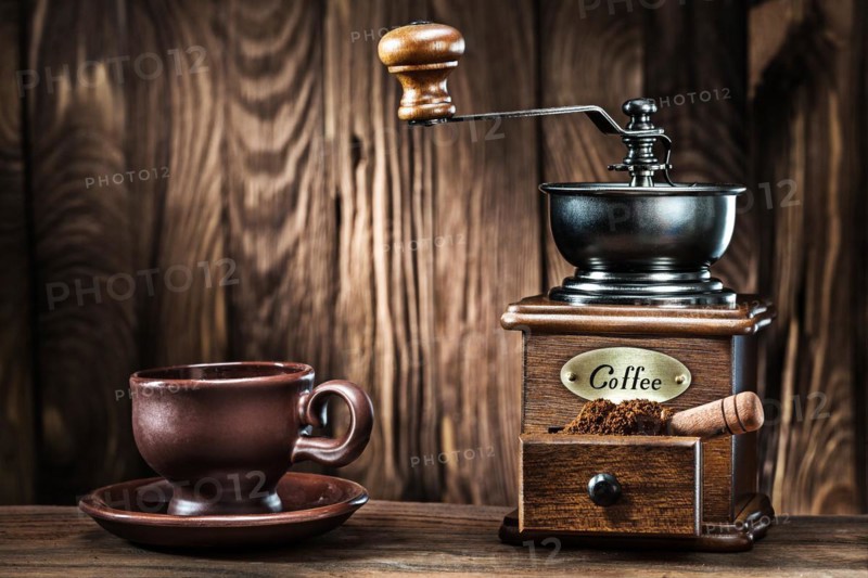 Brown clay coffee cup and vintage wooden mill on old wood background