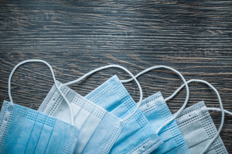 Blue disposable surgical masks on vintage wooden board