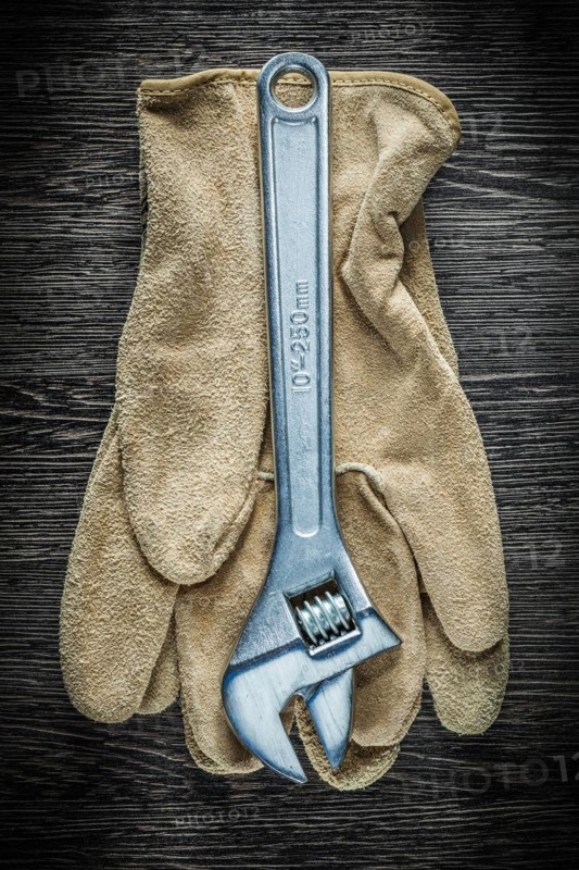 Adjustable spanner safety gloves on wooden board