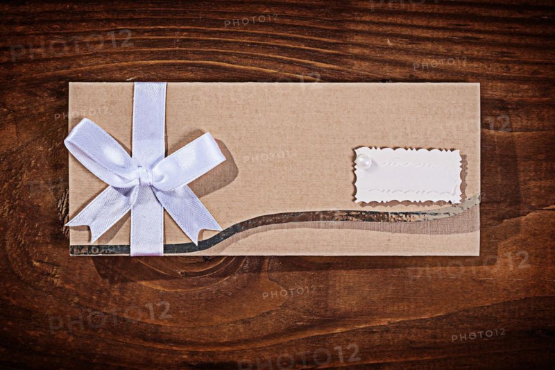 Light brown wedding invitation envelope on an old wooden board