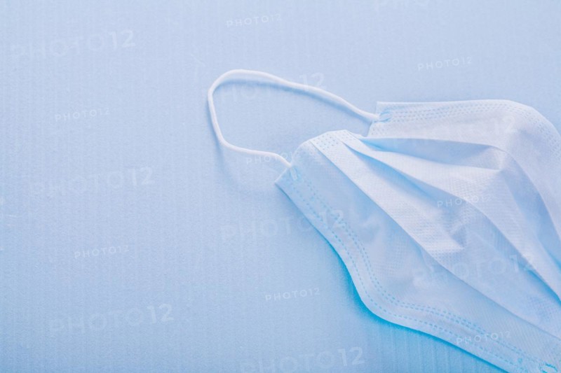 Disposable face mask on blue background with copy area